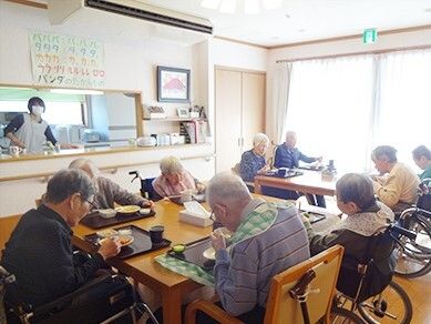 施設内のリビングスペースで食事をしている高齢者の様子。