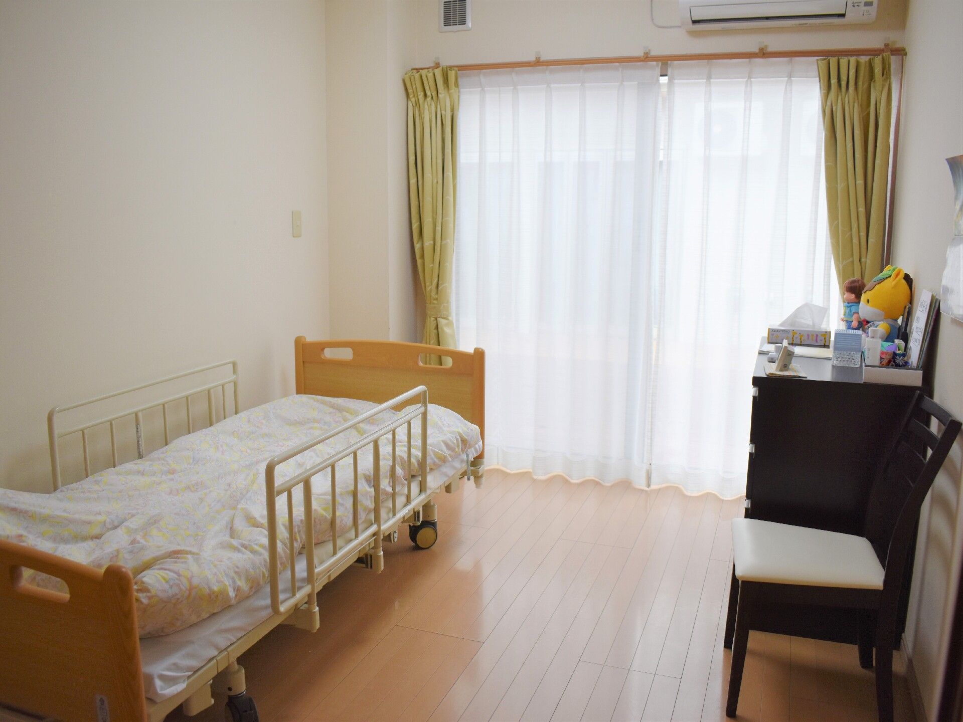 屋外で車いすに乗って散歩を楽しむ男性入居者と付き添いのエプロン姿の女性スタッフ。