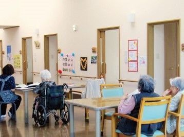 共有スペースでくつろぐ数名のスタッフと、日誌のようなものを書き込んでいるスタッフの様子。