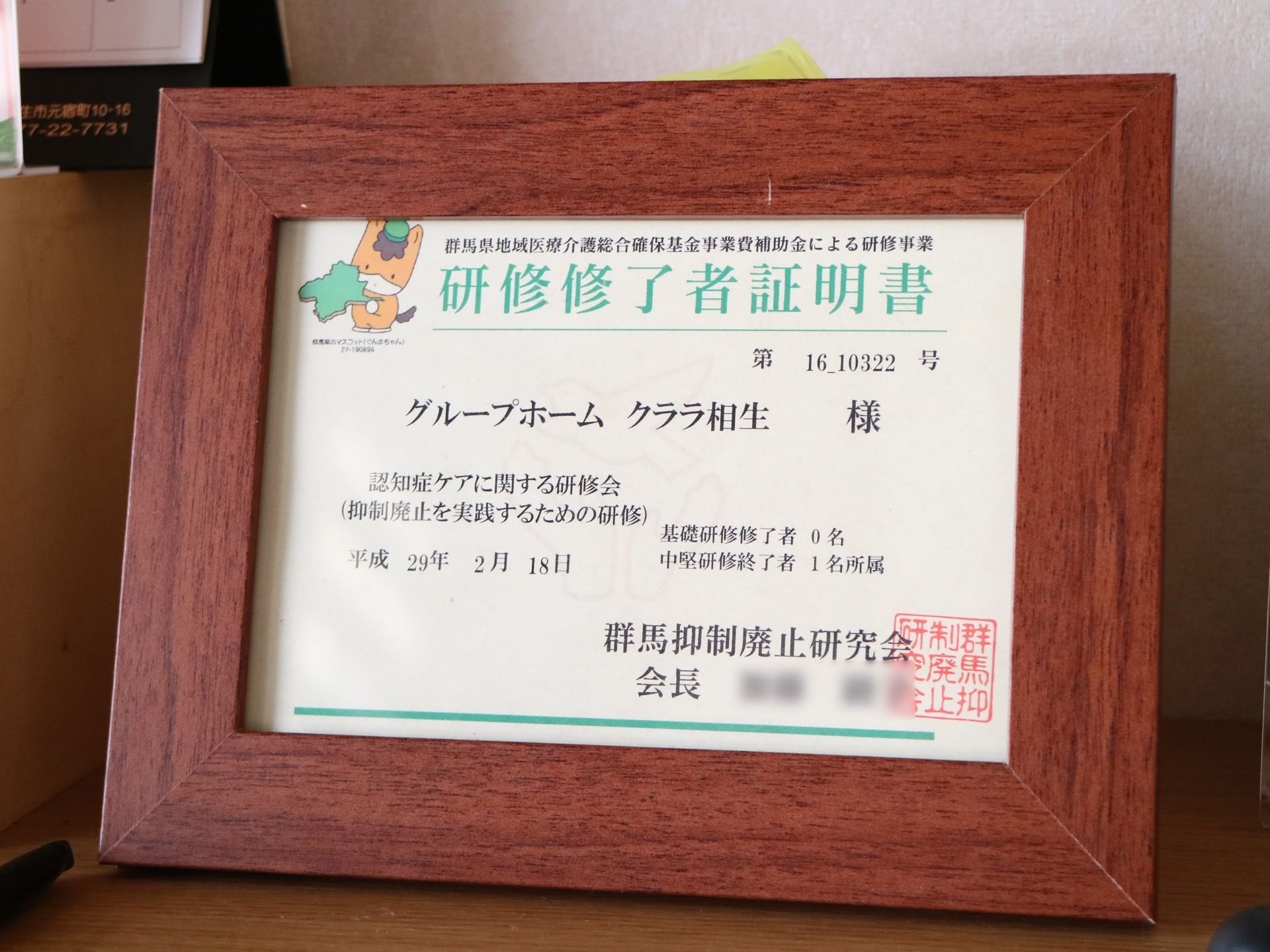認知症ケアの研修終了証明書が、木製のフォトフレームに入れられて置いてある。中堅研修を終了したことが記載されている。