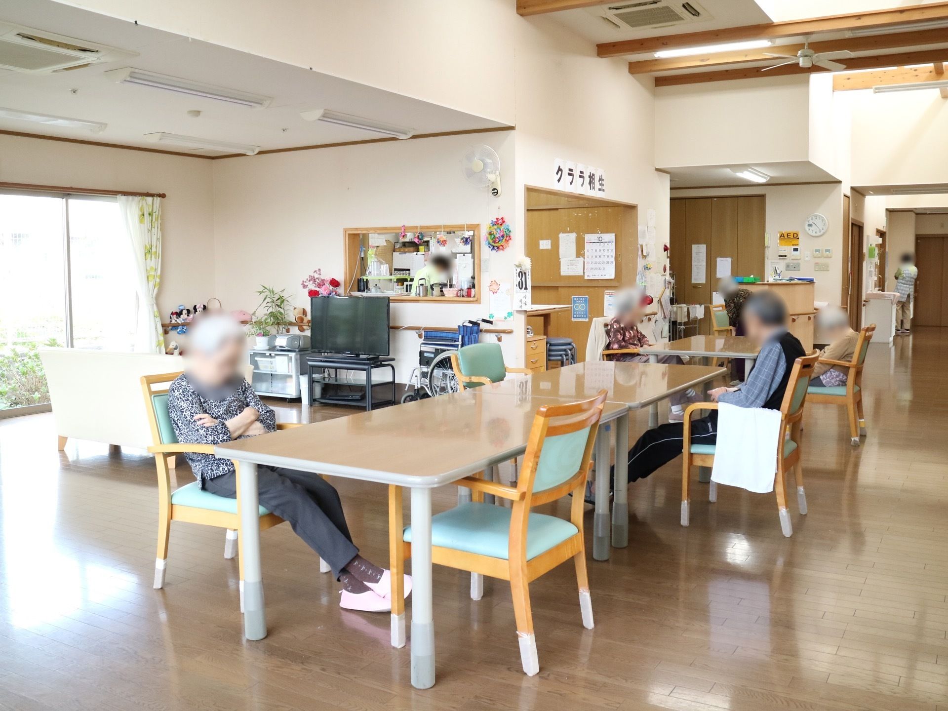 フローリングの広々とした食堂に、ダイニングテーブルと椅子が設置されている。天井には空調やシーリングファンが設備されている。
