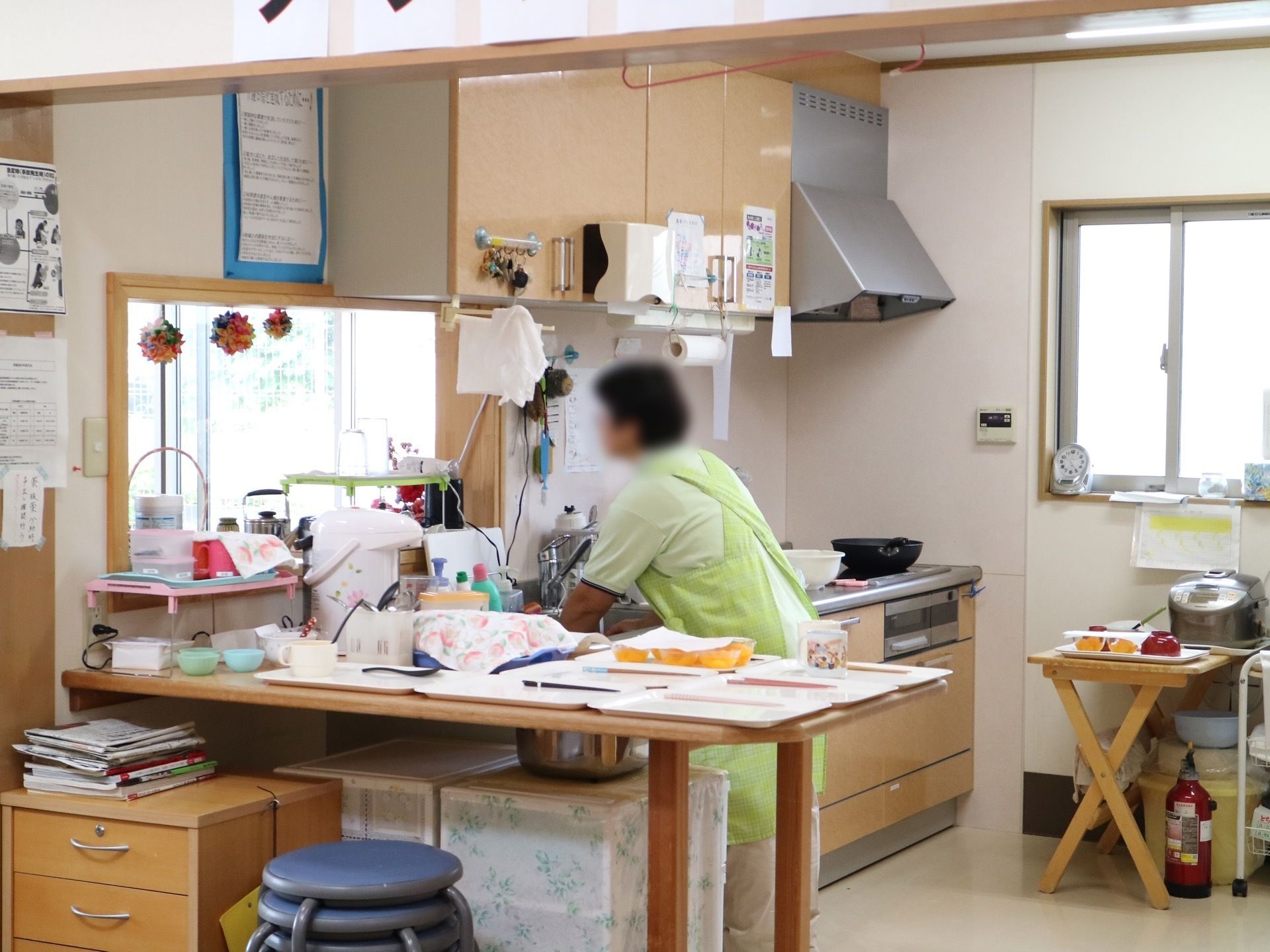 エプロンをしたショートカットのスタッフがキッチンで作業をしている様子。