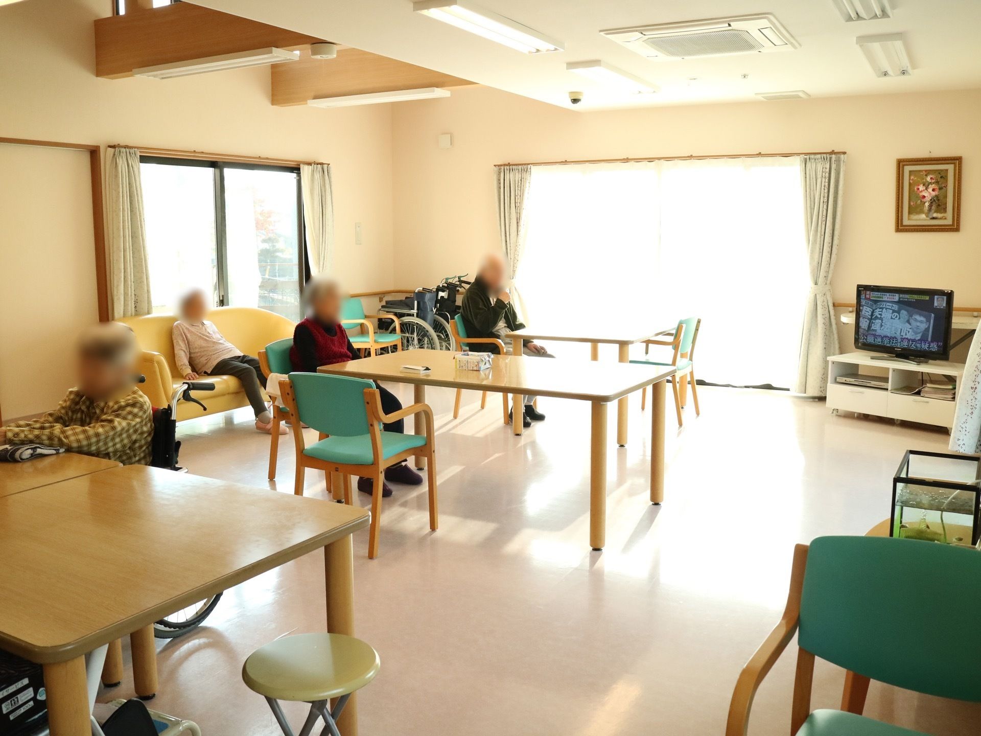 窓から光が差し込む明るい食堂には、テーブルが間隔を空けて設置されている。部屋の隅にはテレビが置かれており、壁には絵画が飾られている。