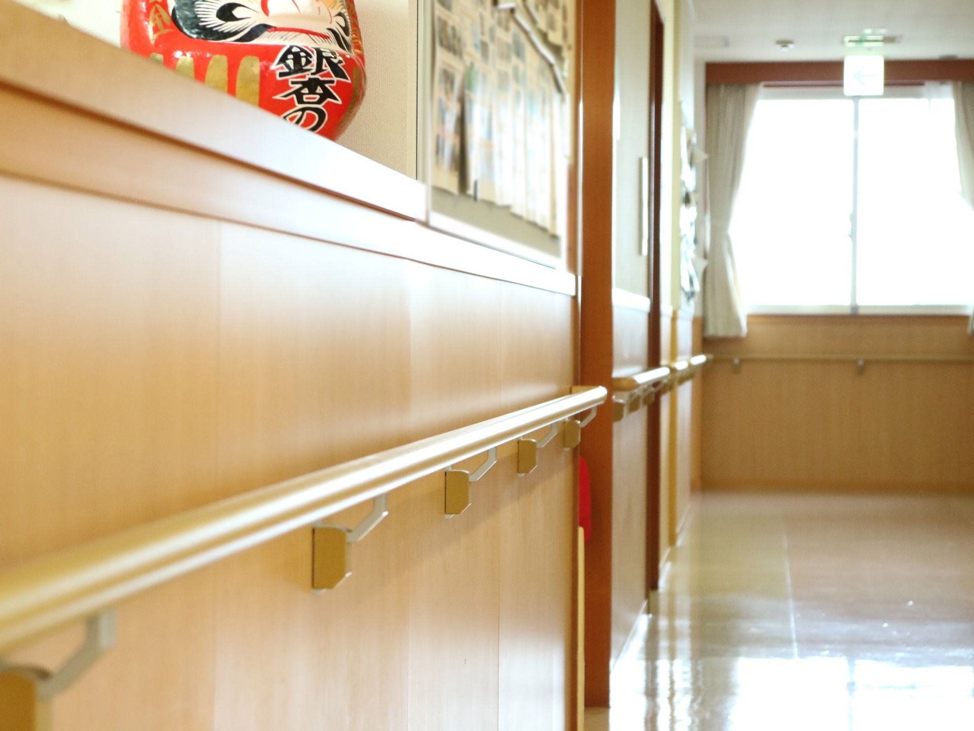 通路の前方には腰高の窓があり、カーテンが束ねられている。壁には手すりが付いていて、掲示板が設置されている。