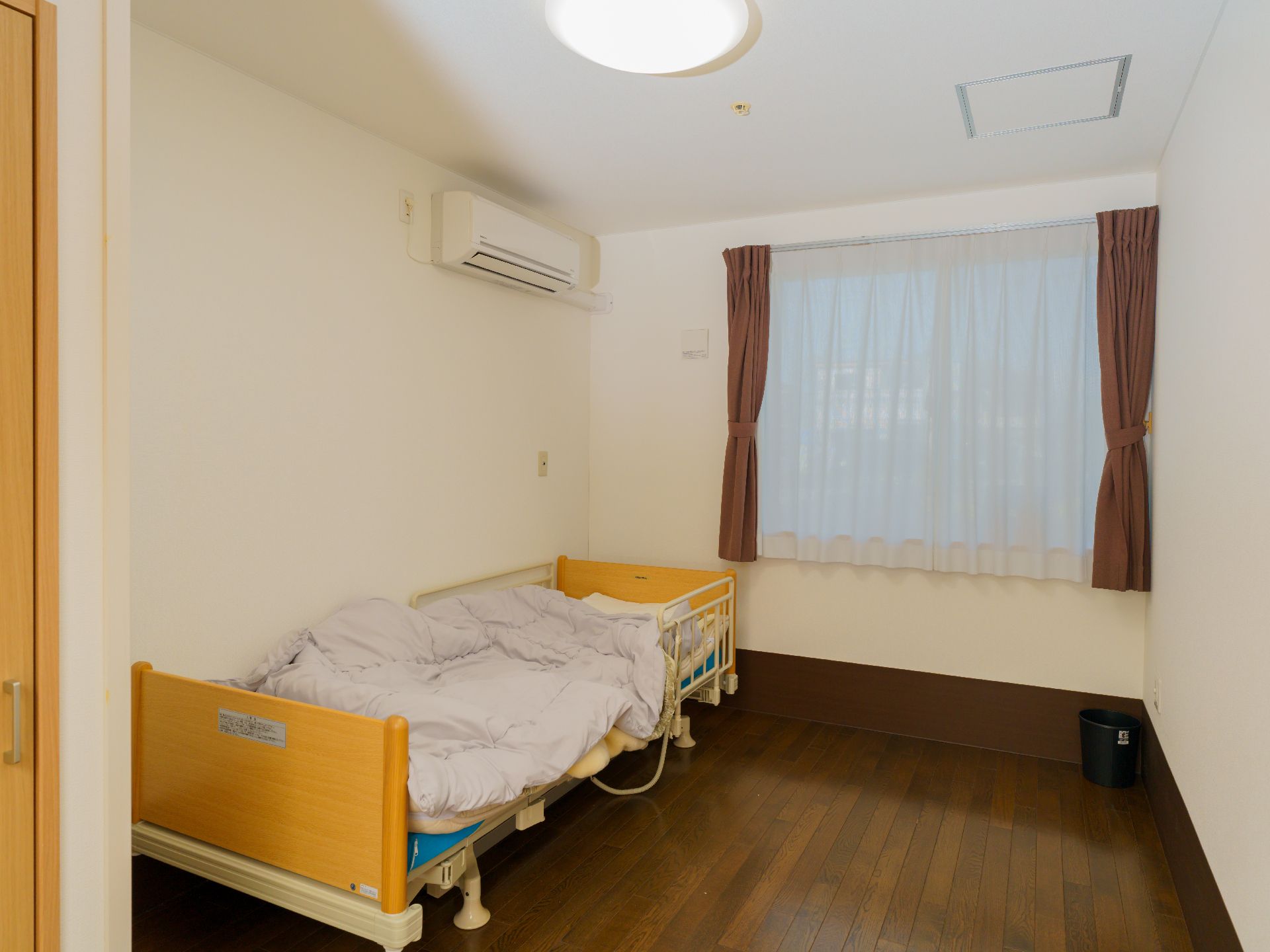 照明の明かりが付いていて、介護ベッドが置かれている居室