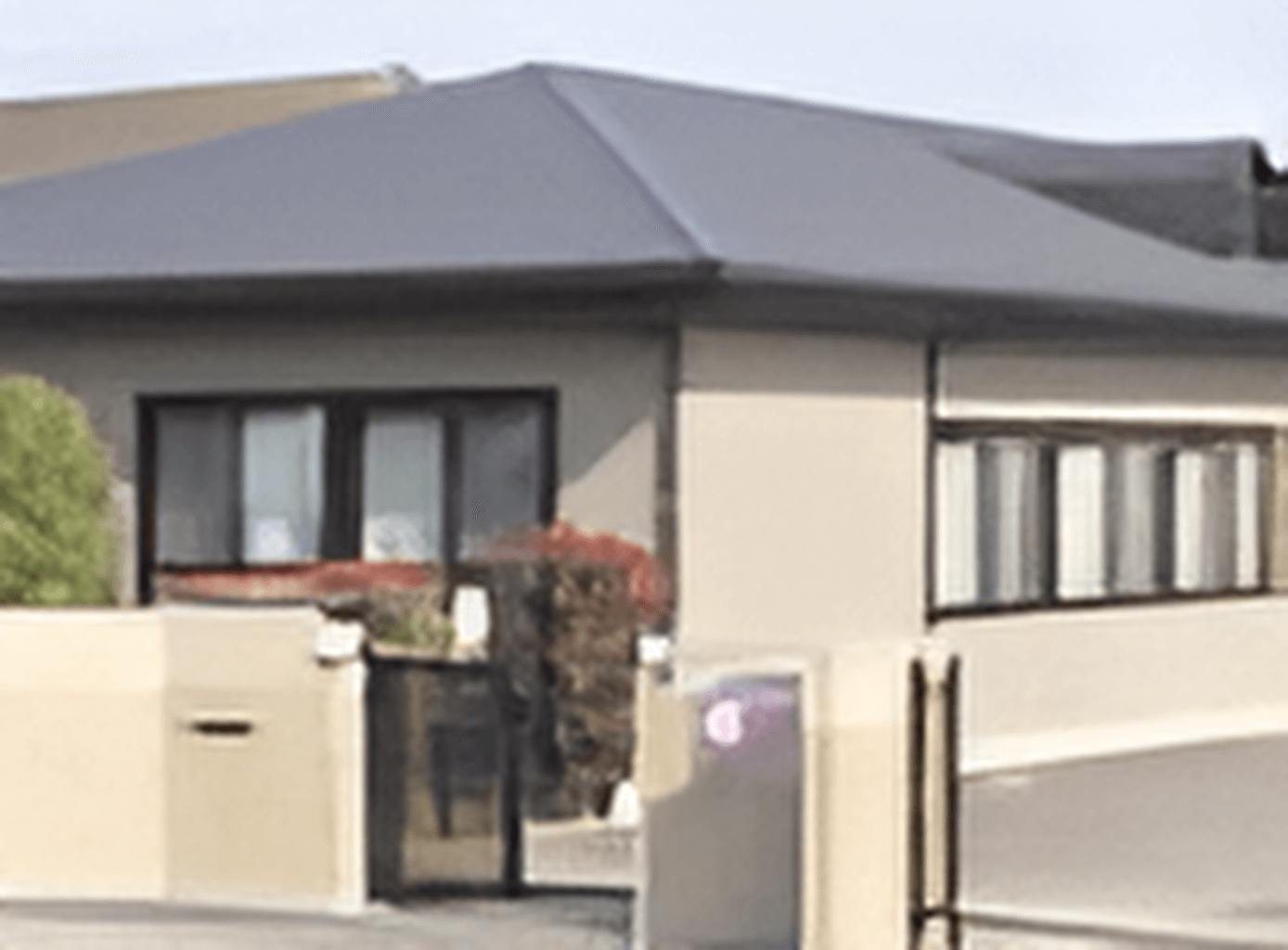 平屋建ての建物はグレーの瓦屋根が付き、和の雰囲気が漂う。玄関には門があり、木も植えられている。