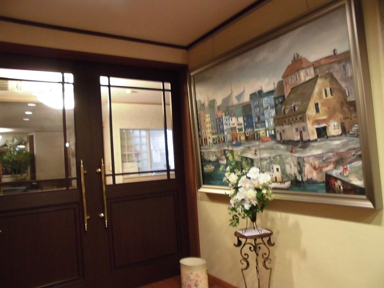 海外の街並みが描かれた大きな絵画が飾られているスペース。白いバラのアレンジメントもある。