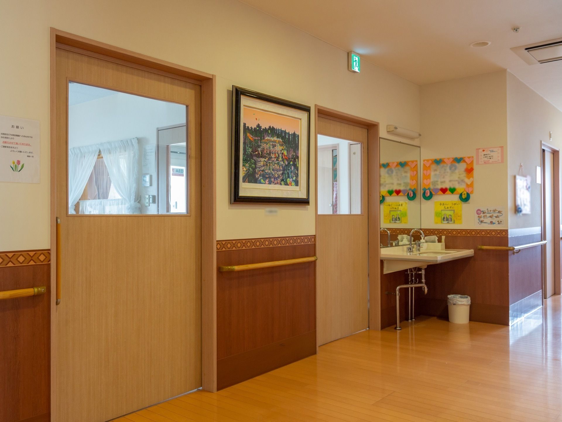 開閉幅の広いスライド式扉を備えた廊下である。壁には絵画のほか、施設スタッフのお手製の装飾が飾られている。廊下の一角には洗面台がある。