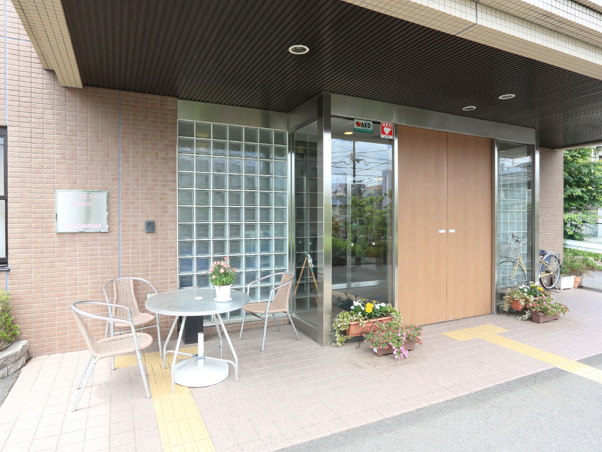 エントランスの入り口には、自動ドアを設置している。また玄関の左手には、イスとテーブルが置かれている。