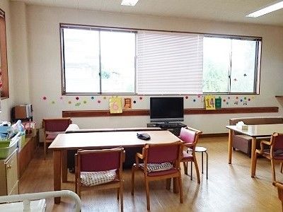 テレビが置かれた食堂には、食卓テーブルが複数置かれている。テレビの後ろ側の窓が大きく、とても明るい雰囲気。