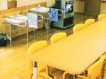 黄色がかったテーブルとイス。向こう側に手洗い場とテレビがある。