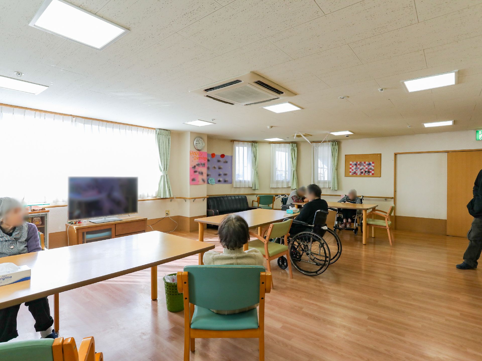 テレビが設置され、テーブルを挟んで椅子が多く置かれている共有スペース
