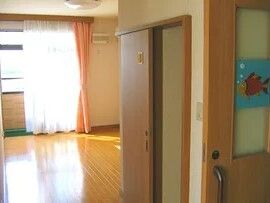 トイレ付きのフローリングの部屋には家具はなく、カーテンが付いた窓がある。居室のドアは引き戸。