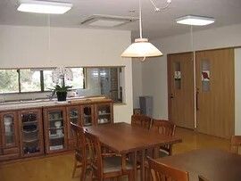 ダークブラウンの家具でまとめられたリビングダイニング。木製のダイニングテーブルが置かれ、花も飾られている。