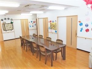 シックな色合いの家庭用サイズの長机と椅子がたくさん並べられているリビング