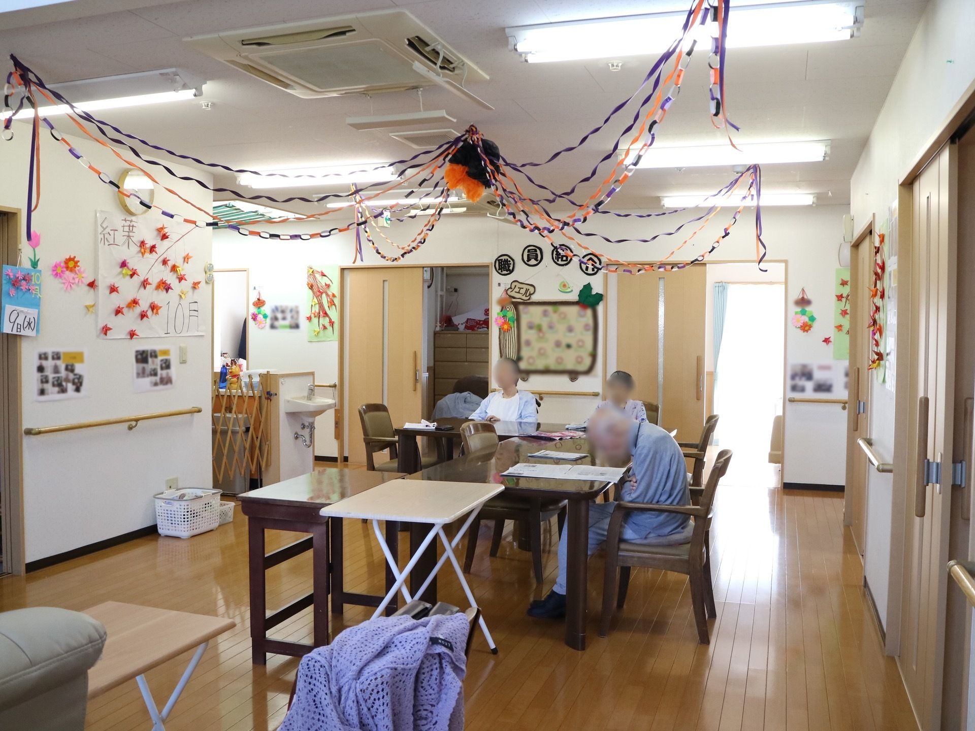 広々としたダイニングに、１人ずつ座ることができるテーブルセットがたくさん置かれている。天井に紙飾りがほどこされている。