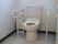 温水洗浄便座が取り付けられた様式トイレの図である。便座の両側に固定式の手すりがある。右手に流し台が見えている。