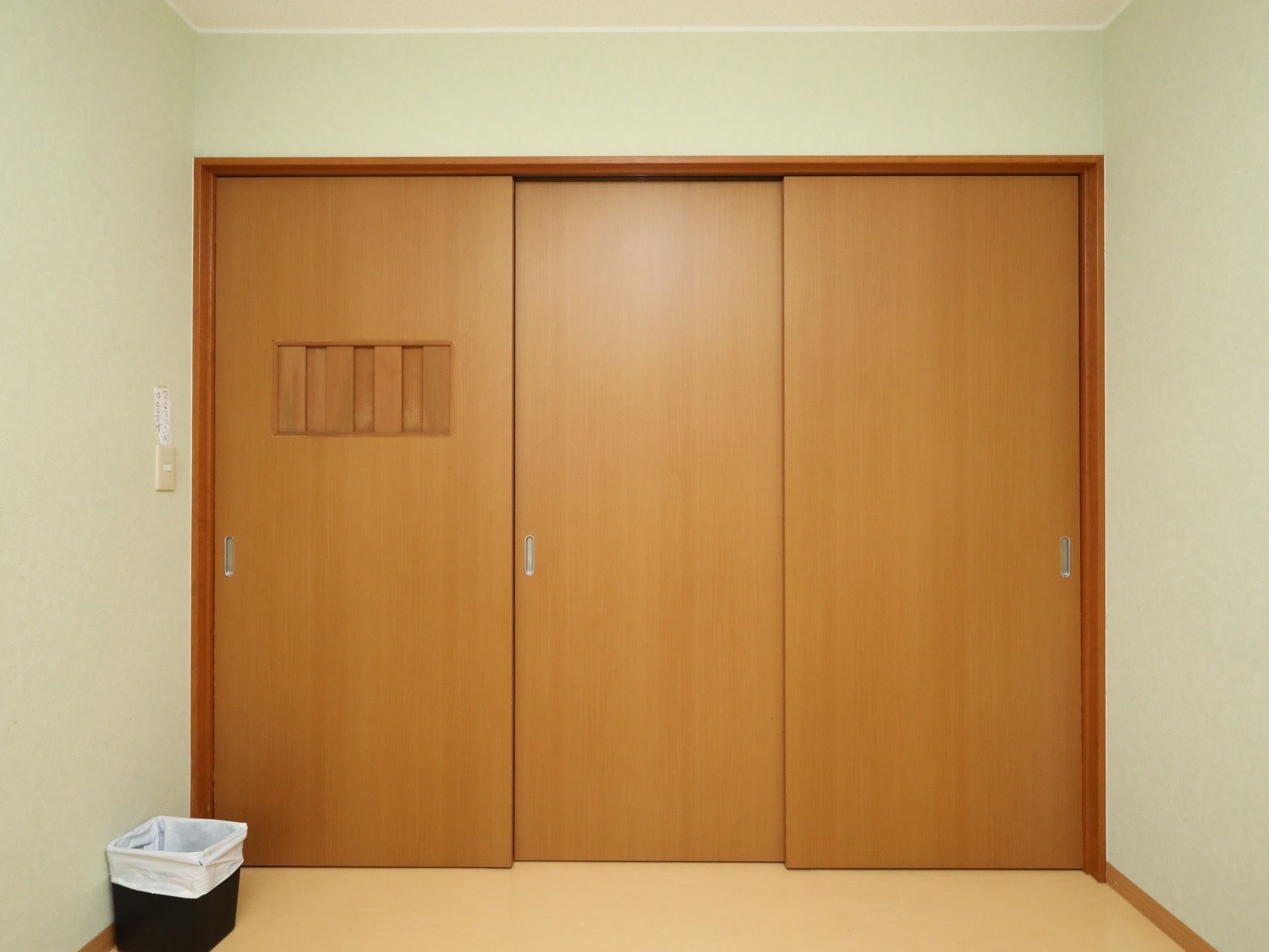 居室にはクローゼットが設置されている。木製の三枚扉で、横にスライドすることで開け閉めできる。黒い小さなごみ箱もある。