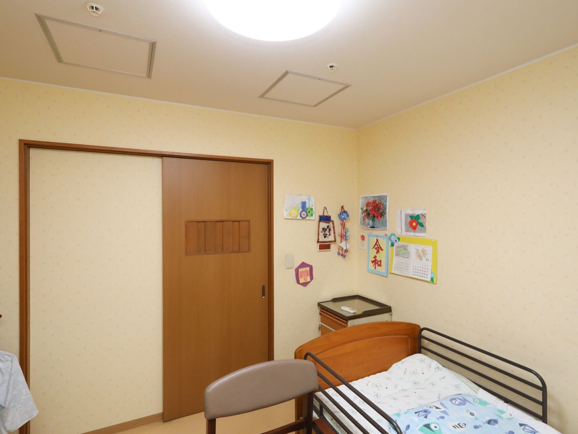 居室はスライド式のドアで、丸い蛍光灯が天井に付いている。壁にはベッドがあり、両側に茶色い手すりが付いている。