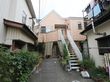 施設の建物は住宅街の一角にあり、両隣は民家となっている。施設へ通じる通路の両側には、数多くのプランターが置かれている。