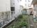 建物の裏側の庭である。複数の植物が植えられている。隅には物置があり、洗濯物用の物干しも置かれている。