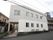 道路に面した、２階建ての窓の多い建物である。玄関までは屋根がついており、手すりも両側に設置されている。
