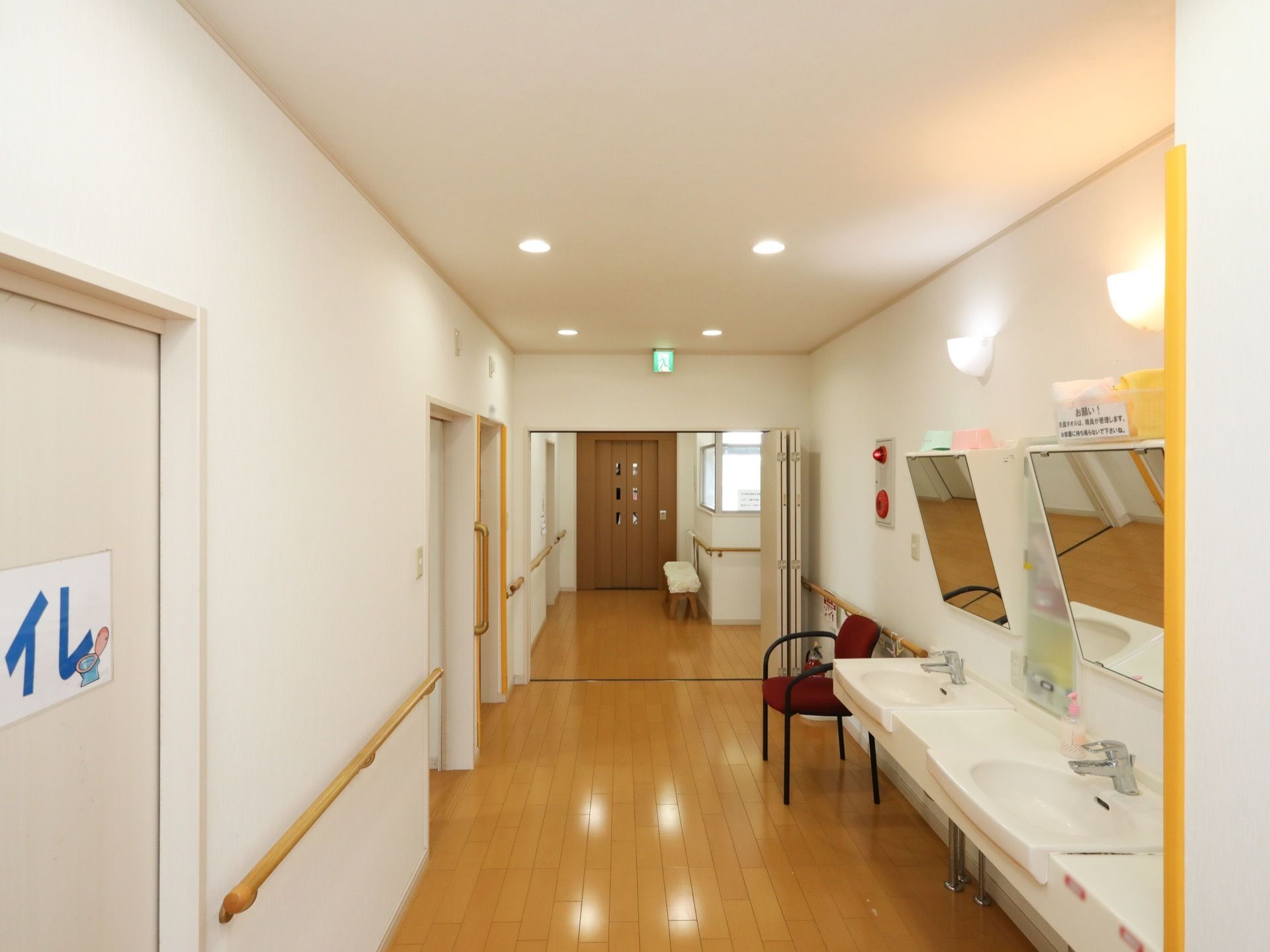 廊下の幅は広く、壁には手すりが付いている。トイレの近くには洗面台が並んでいる。洗面台には鏡が付いている。