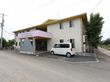 施設は横に長い２階建ての建物である。施設の前には駐車スペースがある。１階入口の屋根の部分には施設名が印字されている。