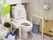 トイレには温水洗浄便座がある。操作パネルが便座の横に取り付けられている。手すりが床に固定されている。
