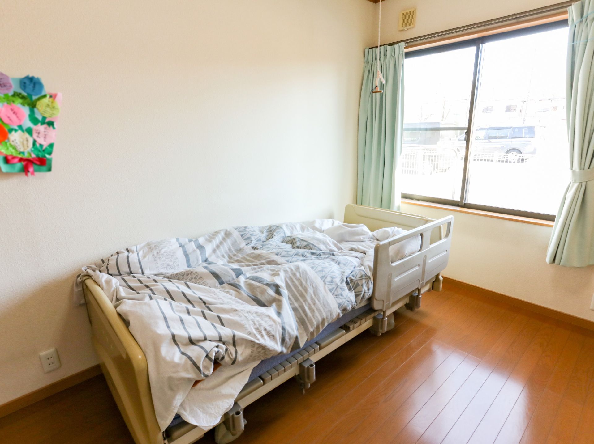 窓から日差しが降り注ぎ、介護ベッドや家具に光が当たっている居室