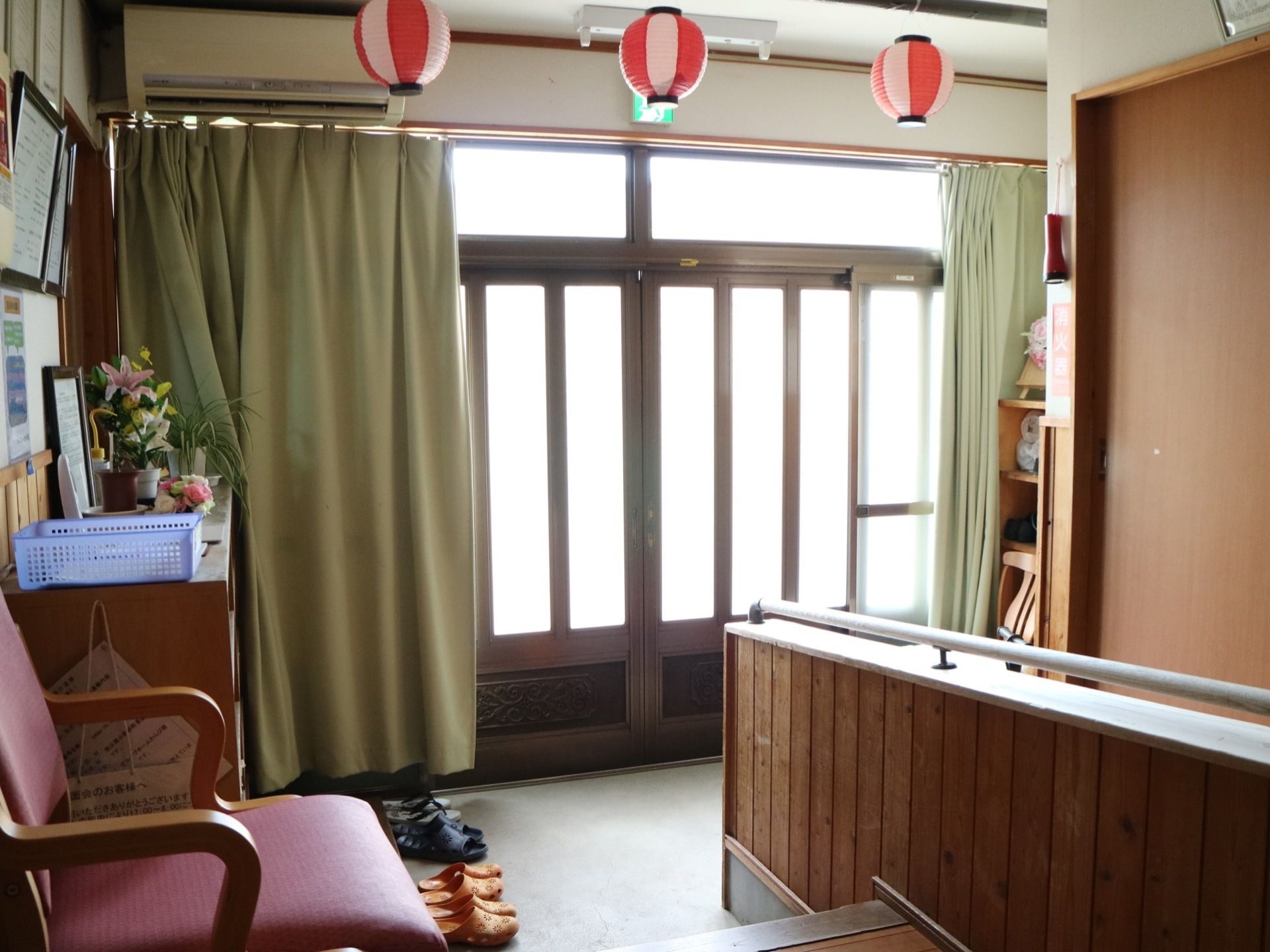 玄関のドアは大きく、引き戸タイプである。内側にはうぐいす色のカーテンが掛かっている。靴を履き替える椅子が置いてある。
