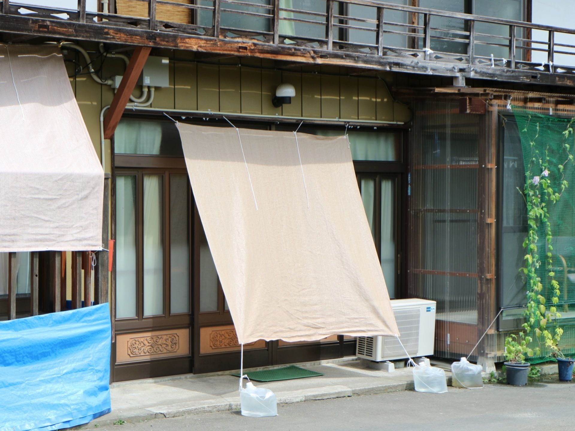 施設入口ドアの前には、日よけのためのシェードを設置している。大きな布を張り、水を入れたビニール袋で重しをしている。