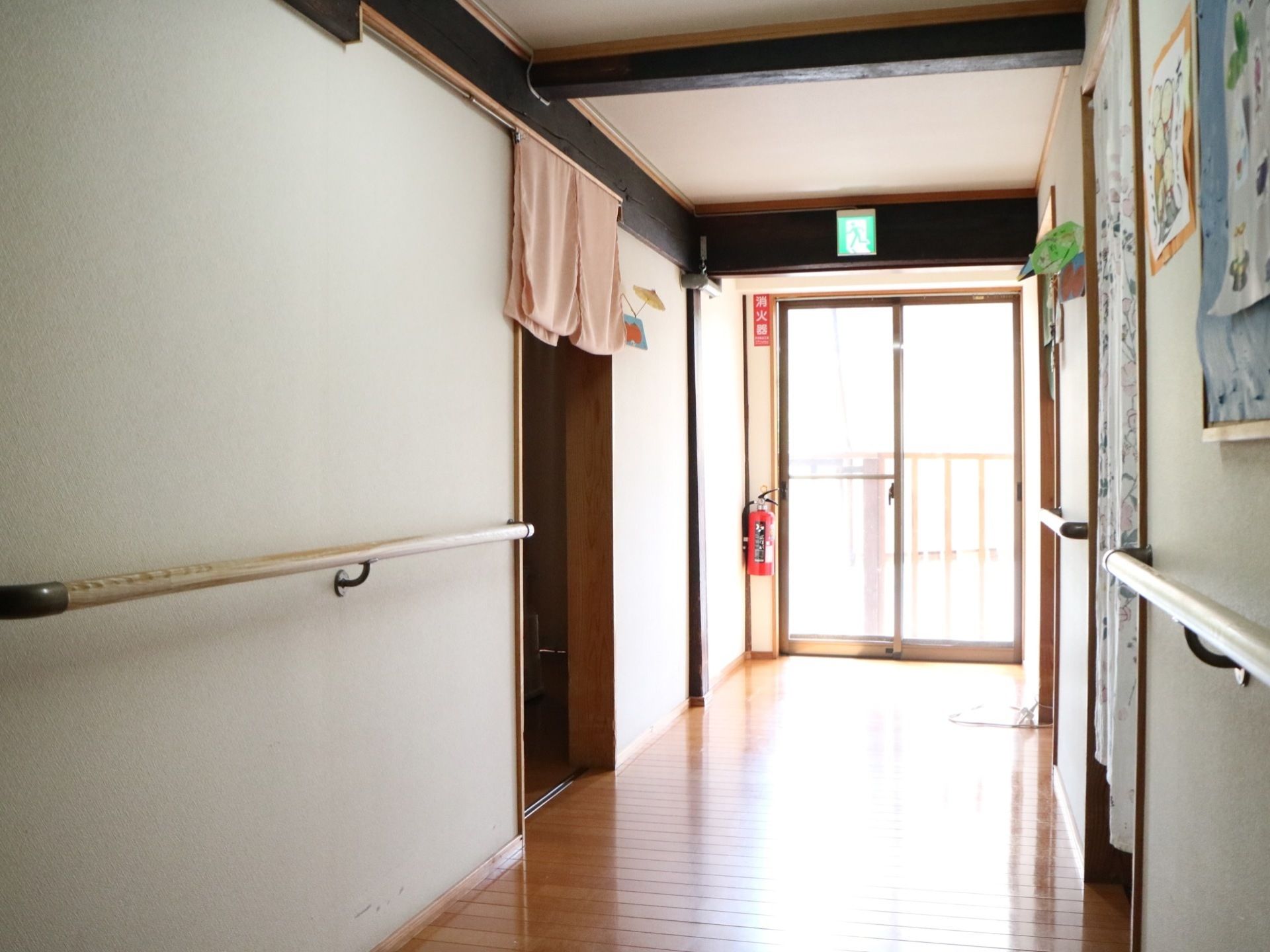 施設内には非常用のドアがある。ドアの上には非常口を示すサインが掲げられている。消火器も置いてある。