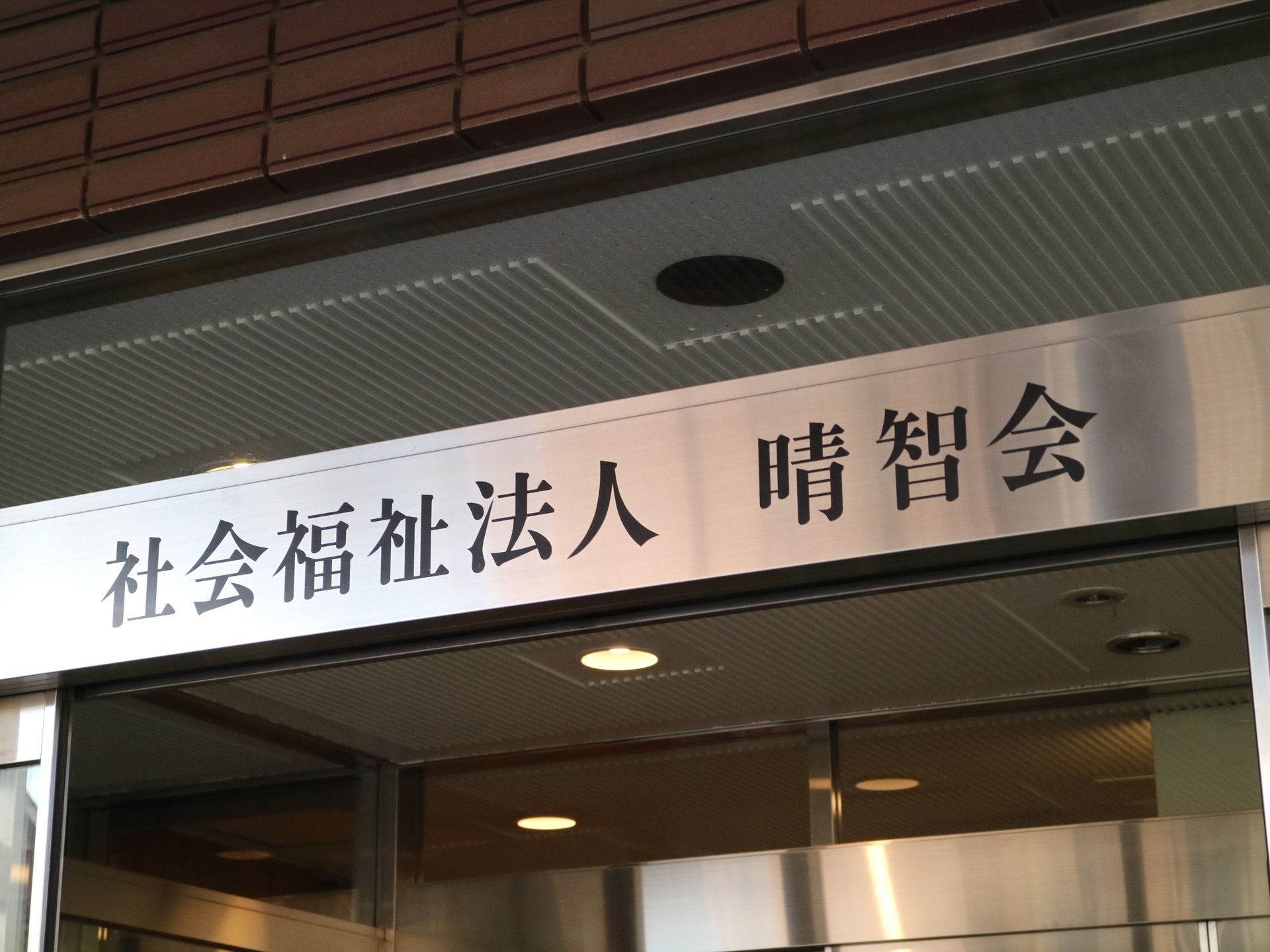 施設の入口扉の上には、施設名が大きくプリントされている。シルバーのステンレス製の枠に、黒い字で書かれている。