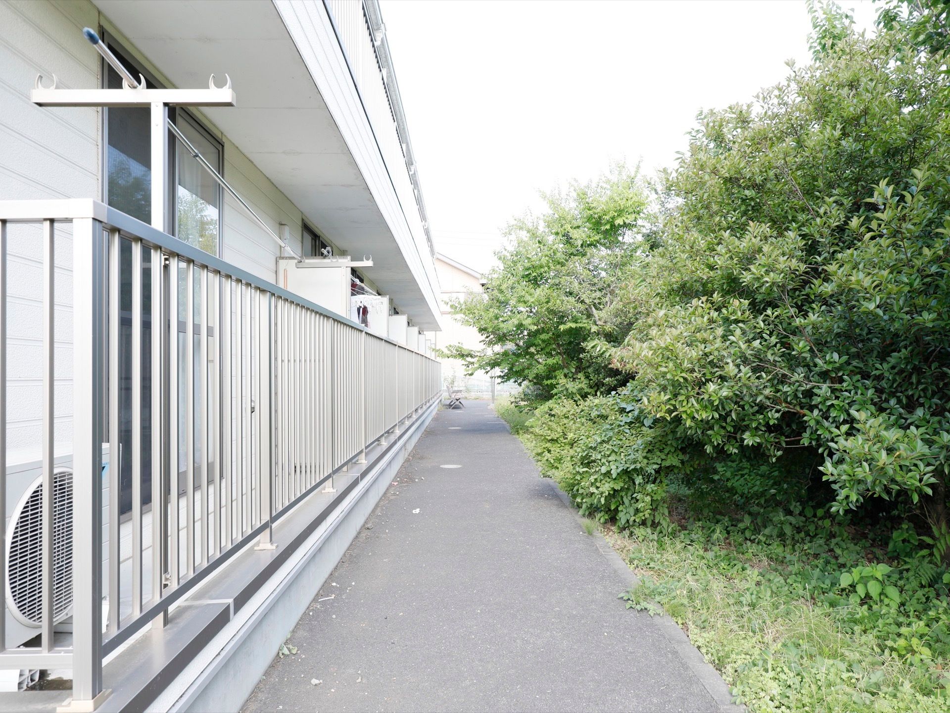 施設周囲は植栽が茂っている。各部屋にベランダがあり、物干し台と物干し竿が用意され、室外機が置かれている。