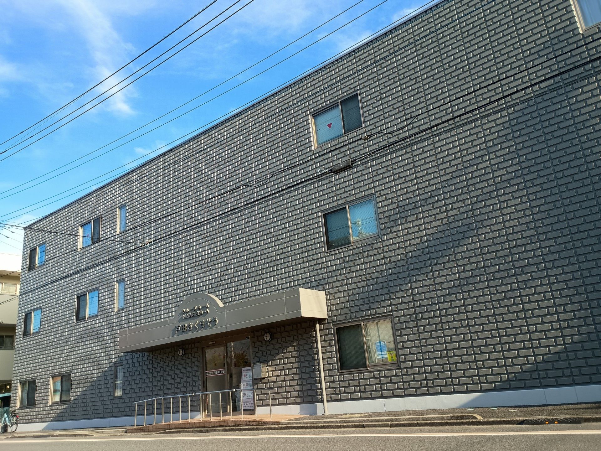 優しいピンク色の外壁の3階建て施設である。周囲は緑が残る住宅地で、静かで穏やかな生活を送ることができる。