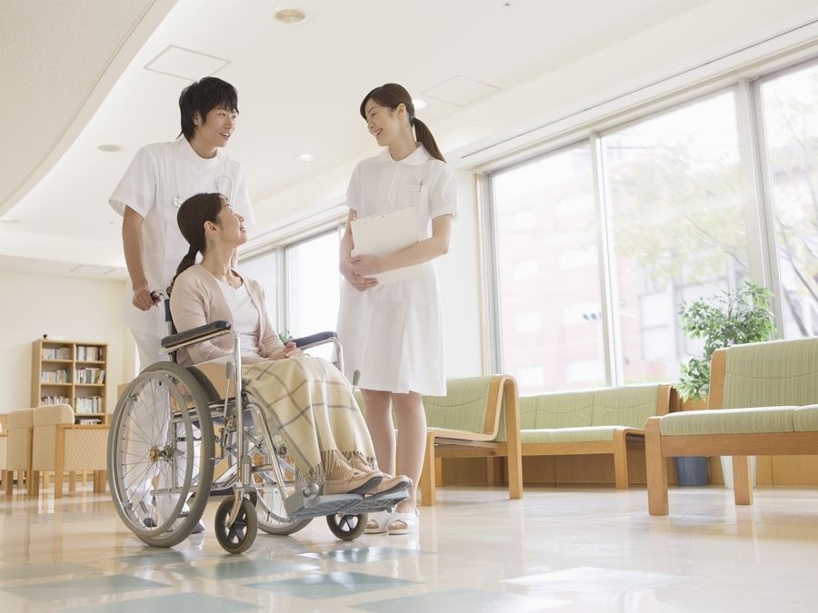 建物の中で話している看護師と医師、患者。明るい日差しが差し込んでいる様子