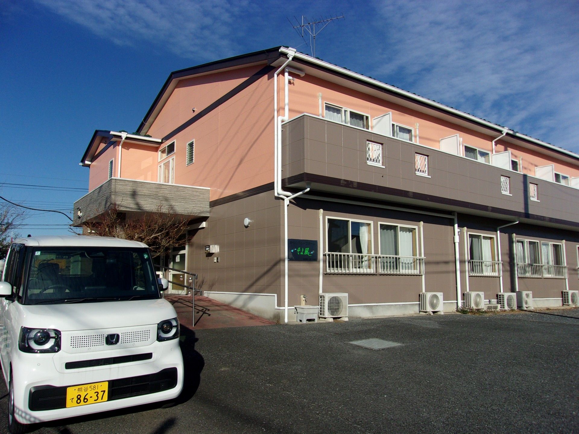 なにかを見て笑顔で手をたたいている高齢女性とスタッフの様子。施設での一場面の写真