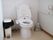 温水洗浄便座の横に大きなゴミ箱を設置し、清潔感があるトイレである。手すりを備え、安全に便座への移動が行える。