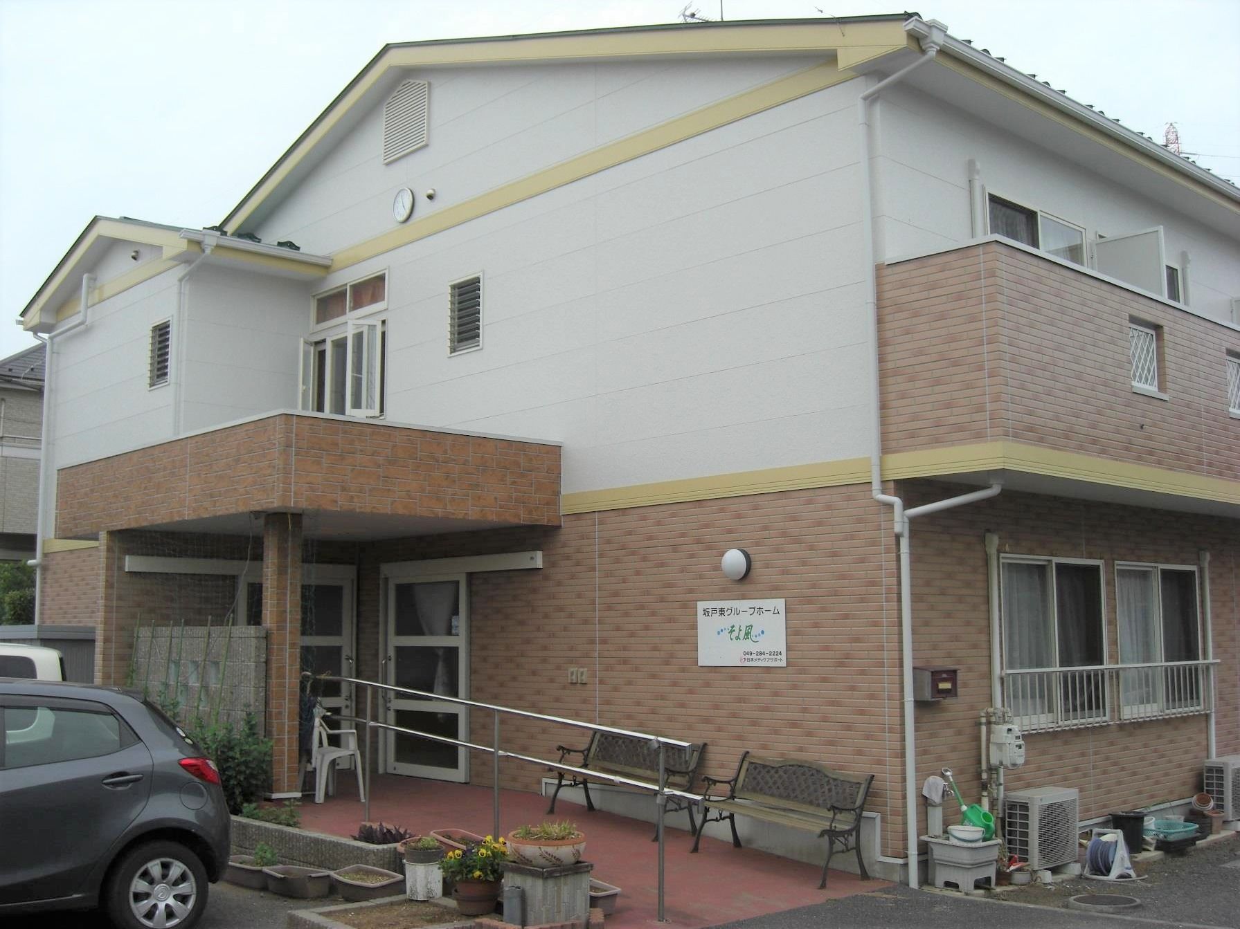 ２階建ての建物は白とブラウンで統一され落ち着いた雰囲気。玄関上には雨除け用の屋根が付けられている。