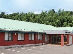 ライトグリーンの屋根が付いている平屋建て平の建物はやエンジ系の外壁で、駐車場がある。