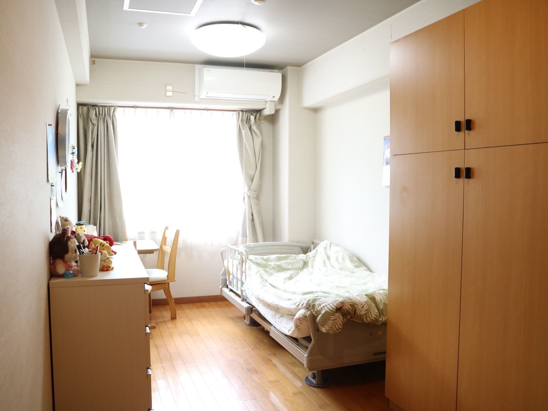 ベッドや収納家具の配置されたエアコン付きのフローリングの部屋