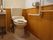 ゆとりある広さのトイレで洗浄機能付温水便座が設置されている。木目調の腰高壁が落ち着いた雰囲気を出している。壁には手すりが付けられている。