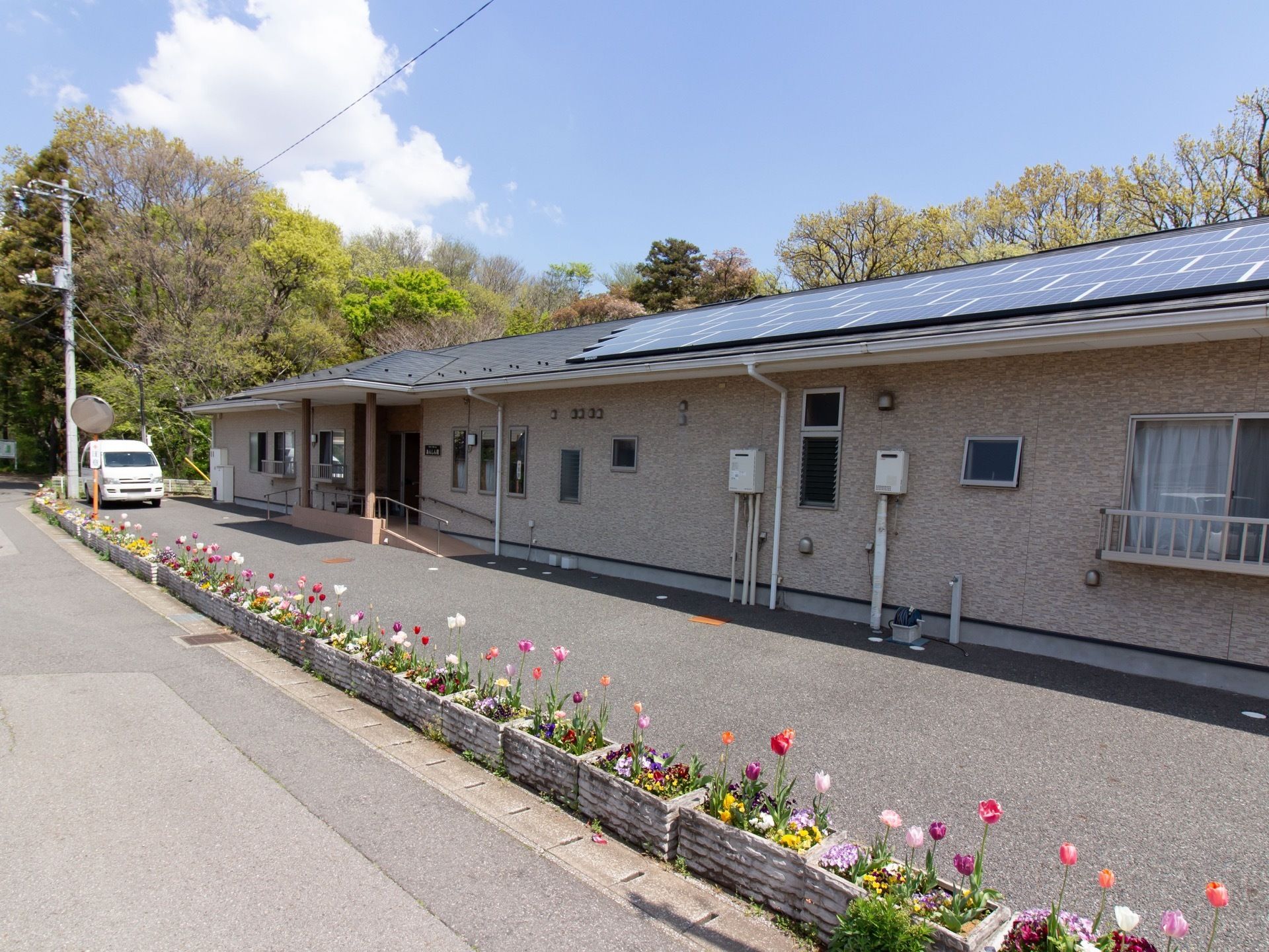 施設は平屋建ての建物である。エントランスにはスロープが設置されている。建物前には、チューリップが植えられたプランターが並べられている。