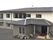 ２階建ての建物はグレーの屋根と白い外壁で落ち着いた雰囲気。玄関先にはプランターが置かれている。