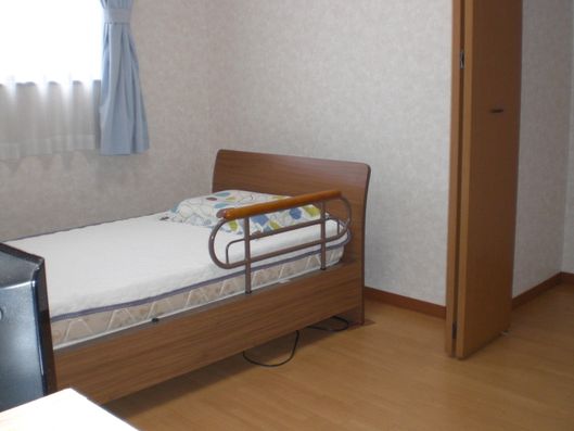 シンプルなつくりの居室。シングルのベッドと段差のない床が見える。