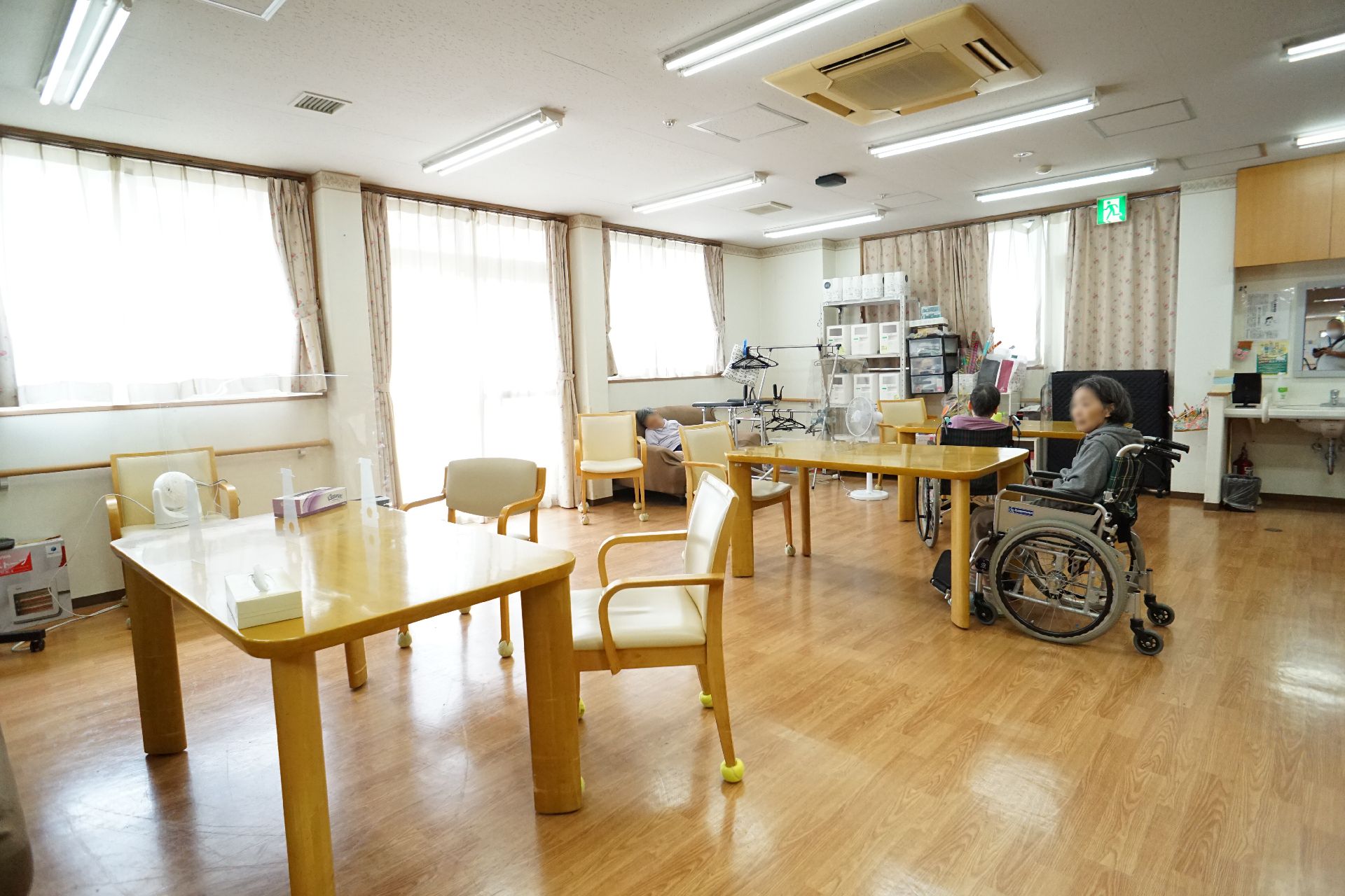 木製の机と椅子が置かれた壁１面が窓ガラスの広間