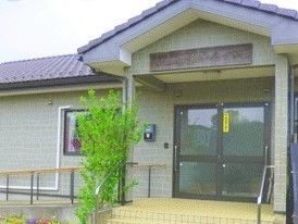 和風の平屋建ての建物。玄関先には木が植えられ、階段やスロープには手すりが付いている。