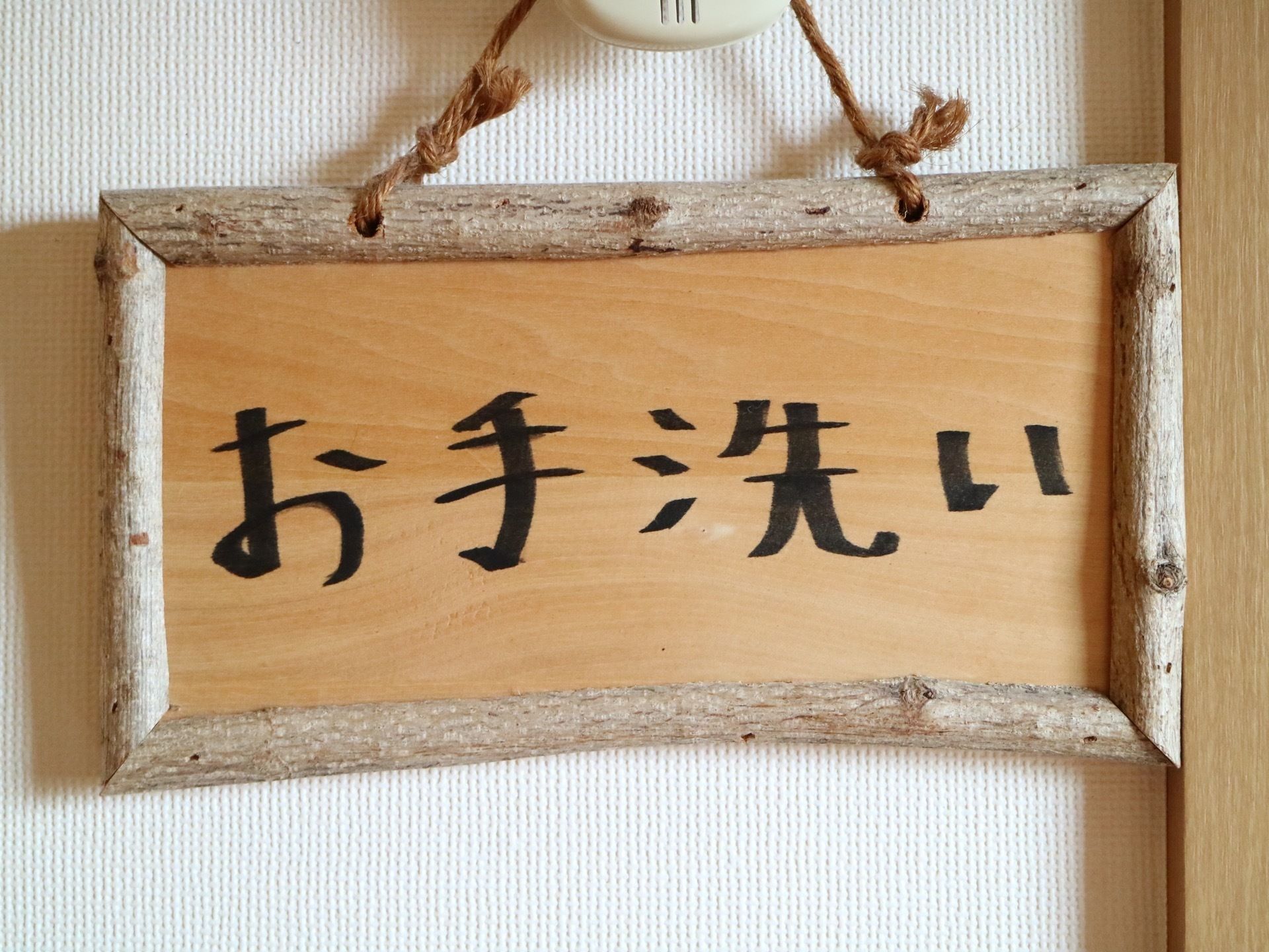 トイレの前にはお手洗いと書かれた看板がかけられている。文字は手書きで、ボードとフレームは木で作られており、自然を感じさせる。