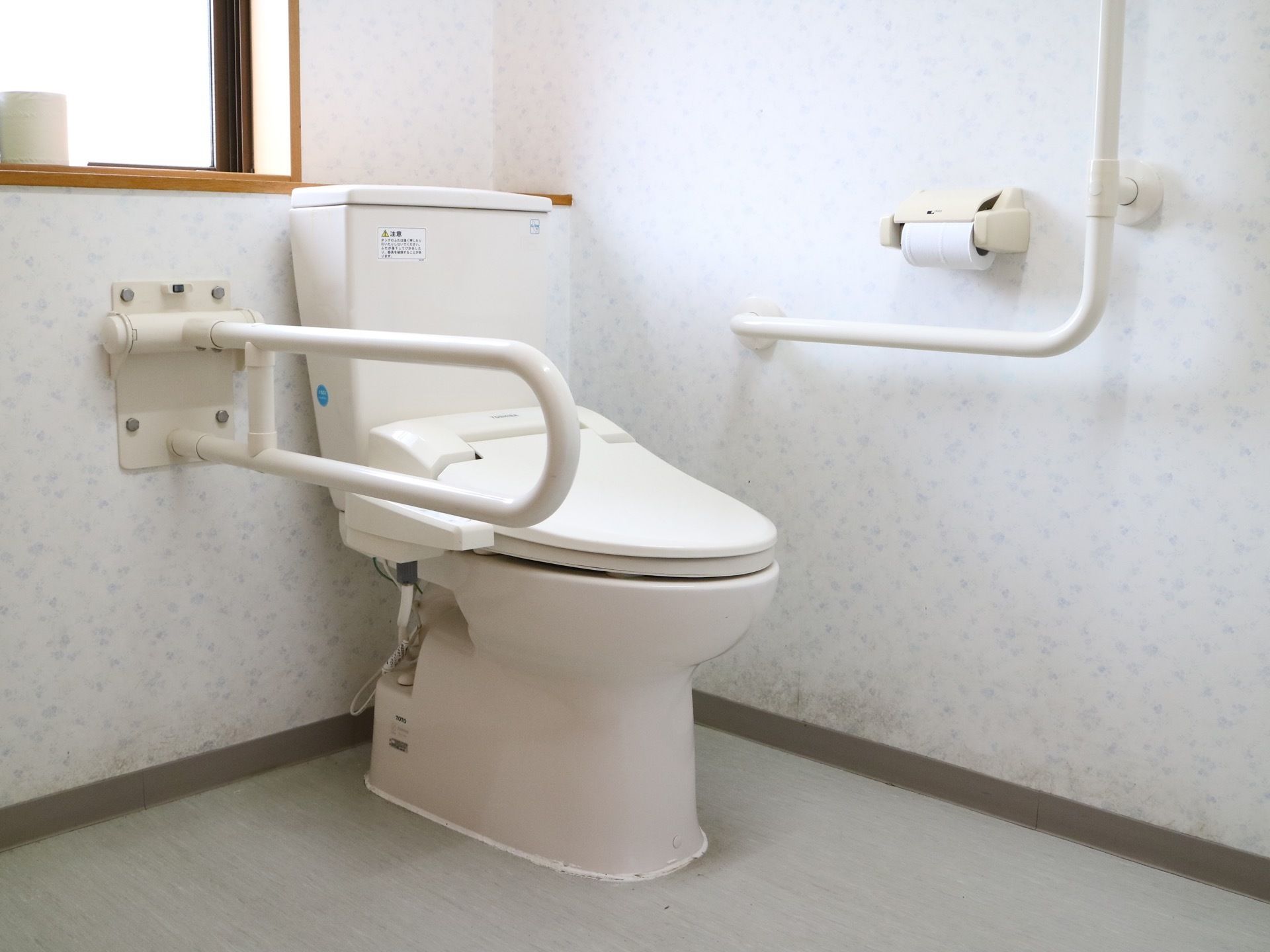 温水洗浄機能付きの洋式トイレである。個室内は清掃が行き届いており、各所に手すりが設けられているので安心。